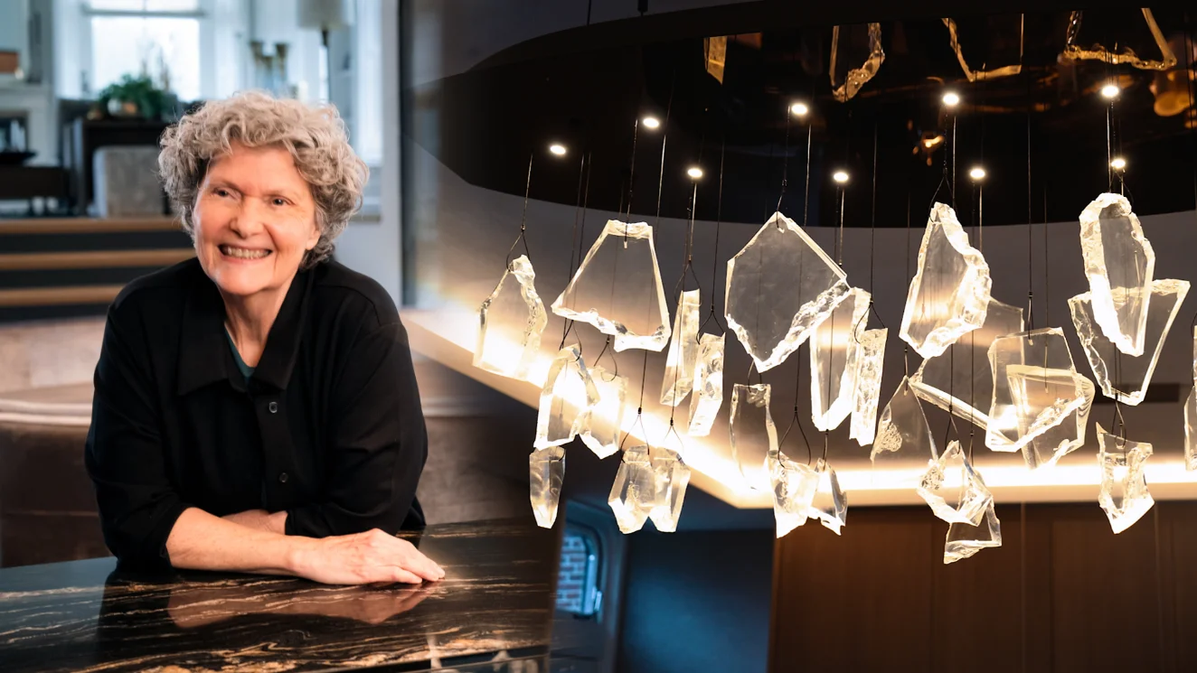 Kunstenares Louise Cohen naast een verlicht kunstobject met hangende glazen elementen